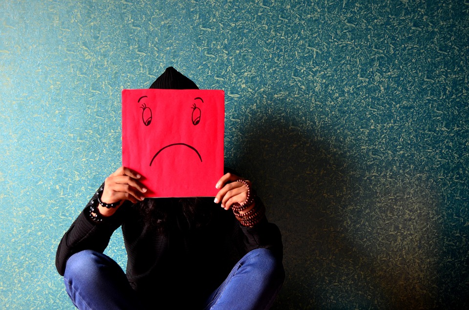 man hiding his face with sad face poster